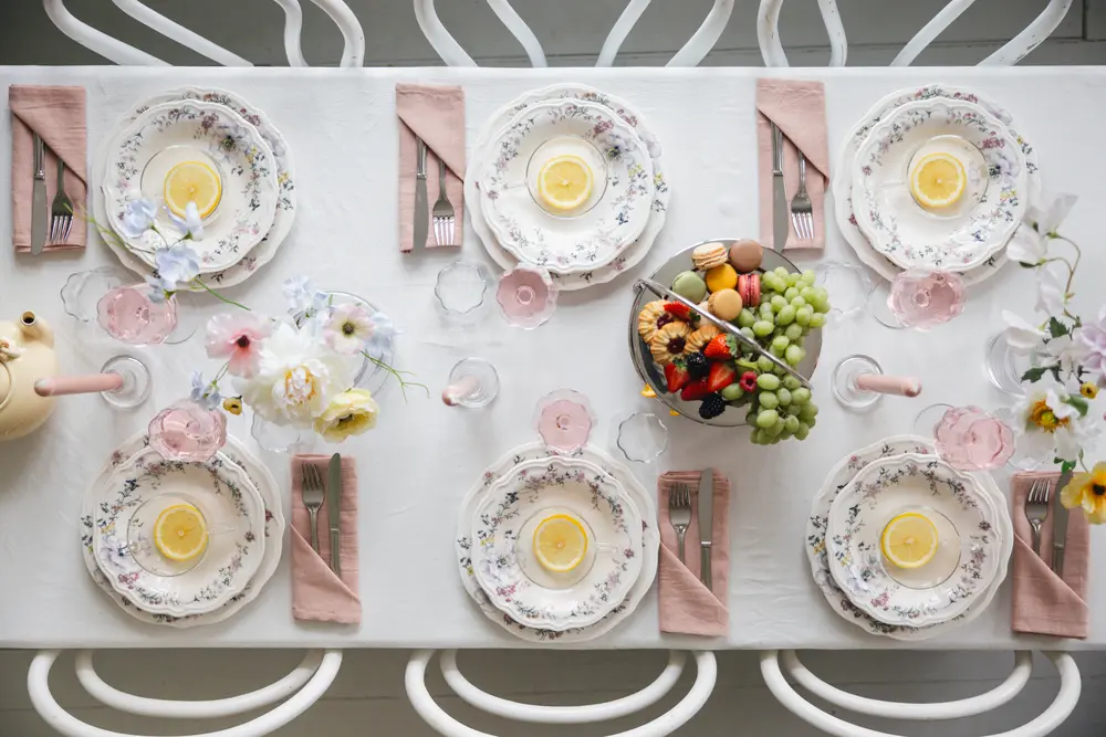 Afternoon in Bloom -pöytä ylhäältä: kukkalautaset, sitruunatee ja vaaleanpunaiset servetit